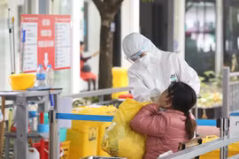 Nhân viên y tế bệnh viện Thanh Nhàn lấy mẫu xét nghiệm COVID-19 cho người đến khám có triệu chứng. (Ảnh: Minh Quyết/TTXVN)