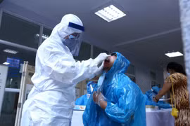 Nhân viên y tế lấy mẫu dịch hầu họng để xét nghiệm bằng phương pháp RT-PCR cho người dân trở về từ Đà Nẵng tại Trung Tâm Y Tế quận Hai Bà Trưng. (Ảnh: Minh Quyết/TTXVN)