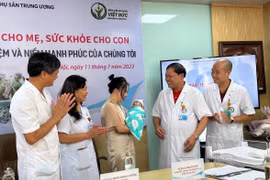 Em bé trong vòng tay của các y bác sỹ và gia đình trong ngày được xuất viện. (Ảnh: T.G/Vietnam+)