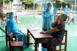 Lấy mẫu sinh phẩm của người dân vùng phong tỏa tại Đà Nẵng để xét nghiệm SARS-CoV-2. (Ảnh: TTXVN phát)