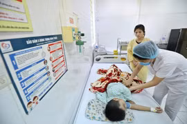 Bác sỹ điều trị cho bệnh nhi mắc sốt xuất huyết. (Ảnh: Minh Quyết/TTXVN)