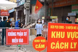 Phun thuốc diệt khuẩn cho người giao hàng nhu yếu phẩm vào khu cách ly tại thôn Hạ Lôi. Ảnh: Minh Quyết/TTXVN)