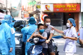Nhân viên y tế hướng dẫn người dân làm thủ tục xếp hàng lấy mẫu xét nghiệm theo phường đã đăng ký. (Ảnh: Minh Quyết/TTXVN)
