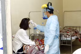 Nhân viên y tế đo thân nhiệt cho bệnh nhân bị cách ly. (Ảnh: Dương Ngọc/TTXVN)