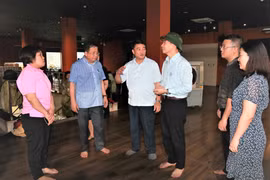Đại diện Trung tâm Y tế quận Hoàn Kiếm báo cáo nhanh với đoàn kiểm tra về công tác đáp ứng y tế tại điểm chợ Hàng Bè. (Ảnh: PV/Vietnam+)