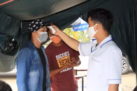 Đo thân nhiệt người điều khiển phương tiện giao thông tại chốt kiểm dịch. (Ảnh: Đặng Tuấn/TTXVN)