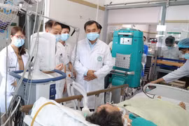 Thứ trưởng Bộ Y tế Trần Văn Thuấn thăm nạn nhân nặng nhất của vụ cháy nhà trọ đang điều trị tại Trung tâm Hồi sức, Bệnh viện Bạch Mai. (Ảnh: PV/Vietnam+)