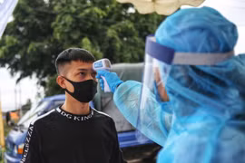 Kiểm tra thân nhiệt người có nhiệm vụ ra-vào thôn Hạ Lôi. (Ảnh: Danh Lam/TTXVN)