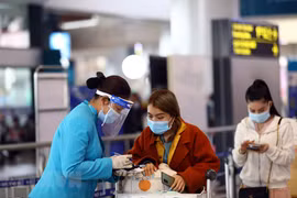 Nhân viên của hãng hàng không hướng dẫn khách làm thủ tục khai báo y tế trước khi vào điểm soi chiếu để lên tàu bay. (Ảnh: Huy Hùng/TTXVN)