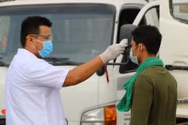 Lực lượng chức năng kiểm soát tại chốt kiểm soát dịch đo thân nhiệt tài xế. (Ảnh: Chương Đài/TTXVN)