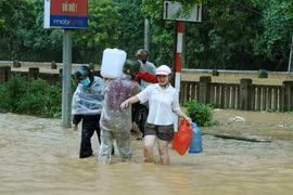 Người dân Lào Cai vượt lũ để có được nước từ khe núi mang về gia đình sử dụng. (Ảnh: Quốc Khánh/TTXVN)