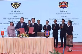Tổng Cục trưởng Tổng cục Quản lý Thị trường Trần Hữu Linh và Vụ trưởng Vụ Cạnh tranh kinh doanh và Kiểm tra Thương mại Lào triển khai ký cam kết trong lĩnh vực quản lý thị trường. (Ảnh: PV/Vietnam+)