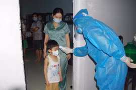 Cán bộ và nhân viên y tế kiểm tra và đo thân nhiệt cho người đang cách ly tại Bạc Liêu. (Ảnh: Chanh Đa/TTXVN)