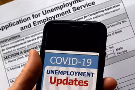Cập nhật tình hình mất việc làm do dịch COVID-19 trên điện thoại tại Arlington, bang Virginia, Mỹ. (Ảnh: AFP/TTXVN)