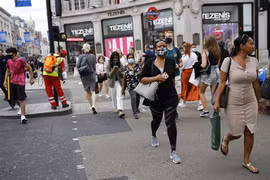 Người dân đeo khẩu trang phòng lây nhiễm COVID-19 khi di chuyển trên đường phố tại London, Anh. (Ảnh: AFP/TTXVN)