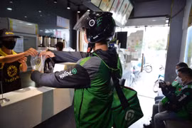 Tài xế Gojek nhận món ở nhà hàng để giao cho khách. (Ảnh: PV/Vietnam+)
