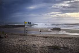 Người dân dỡ bỏ các tấm biển quảng cáo dọc bờ biển tại Costa da Caparica của Bồ Đào Nha trước bão Leslie ngày 13/10. (Ảnh: AFP/TTXVN)