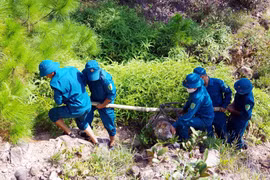 Lực lượng chức năng di chuyển một quả bom tới địa điểm để hủy nổ. (Ảnh: Tá Chuyên/TTXVN)