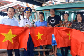 Tặng cờ Tổ quốc cho bà con ngư dân huyện Cát Hải. (Ảnh: Minh Huệ/TTXVN)