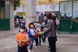 Đo thân nhiệt và nhắc nhở các em học sinh đeo khẩu trang khi vào trường. (Ảnh: Trọng Đạt/TTXVN)