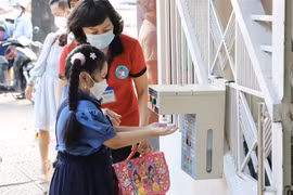 Giáo viên hướng dẫn học sinh rửa tay trước khi vào lớp. (Ảnh: Hồng Giang/TTXVN)
