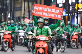 Các tài xế Grab với những băng rôn khẩu hiệu "Grab thu thuế VAT bất hợp lý". (Ảnh: Thành Đạt/TTXVN)