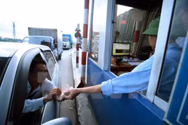 Lái xe cố tình chậm chạp trả từng đồng tiền lẻ tại trạm thu phí BOT. (Ảnh: Phạm Kiên/TTXVN)