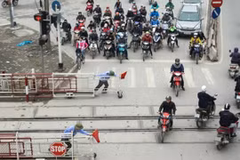 Trên đường Giải Phóng, mặc dù có rào chắn cẩn thận nhưng khi tàu chuẩn bị chạy qua, nhiều người dân vẫn bất chấp tính mạng vượt qua. (Ảnh: Minh Sơn/Vietnam+)