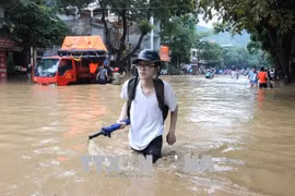 Thí sinh Hà Giang lội nước đến điểm thi trong kỳ thi Trung học phổ thông quốc gia 2018. (Ảnh: TTXVN)