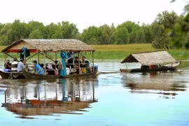 Du khách tham quan Vườn quốc gia Tràm Chim bằng nhà nổi trên sông. (Ảnh: An Hiếu/TTXVN) 