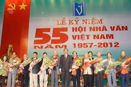 Đồng chí Đinh Thế Huynh tặng hoa chúc mừng lãnh đạo Hội Nhà văn Việt Nam qua các thời kỳ. (Ảnh: Thanh Tùng/TTXVN)