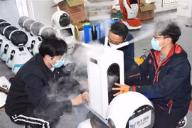 Các kỹ thuật viên kiểm tra robot khử trùng thế hệ đầu tiên tại công ty công nghệ Thanh Đảo, tỉnh Sơn Đông, Trung Quốc. (Ảnh: THX/TTXVN)