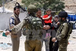 Binh sỹ Israel kiểm tra một gia đình Palestine tại một trạm kiểm soát ở Yatta, phía Nam Hebron. (Nguồn: EPA/TTXVN)