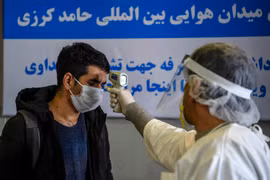 Nhân viên y tế kiểm tra thân nhiệt cho hành khách tại sân bay quốc tế Hamid Karzai ở thủ đô Kabul, Afghanistan ngày 2/2/2020. (Ảnh: AFP/TTXVN)