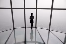 Một người phụ nữ nhìn qua ô cửa ở Seoul bị che phủ bởi bụi mịn. (Ảnh: Reuters)