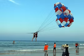 Khách du lịch tham gia trò chơi canô kéo dù tại biển Phạm Văn Đồng (Đà Nẵng). (Ảnh: Trần Lê Lâm/TTXVN)