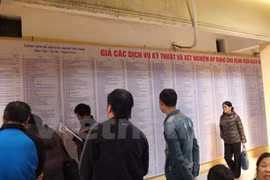 Người dân xem bảng giá viện phí tại bệnh viện Bạch Mai. (Ảnh: PV/Vietnam+)