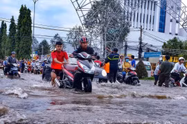 Đường Nguyễn Văn Cừ, quận Ninh Kiều bị ngập sâu, người dân vất vả khi di chuyển. (Ảnh: Thanh Liêm/TTXVN)