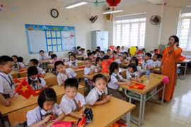 Bàn học được thiết kế cho hai học sinh nhưng vẫn phải xếp ba em vì quá tải. (Ảnh: Minh Sơn/Vietnam+) 