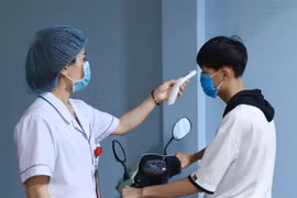 Lực lượng y tế đo thân nhiệt người dân khi vào bệnh viện. (Ảnh: Hoàng Hùng/TTXVN) 