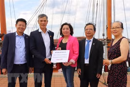 Đại sứ Việt Nam tại Đức, ông Nguyễn Minh Vũ (thứ 2 từ trái sang) tiếp nhận số tiền quyên góp của cộng đồng người Việt ở thành phố Rostock và vùng phụ cận. (Ảnh: Mạnh Hùng/TTXVN) 