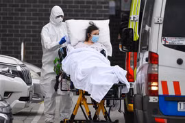Nhân viên y tế chuyển bệnh nhân COVID-19 lên xe cứu thương tại thành phố Melbourne, Australia. (Ảnh: AFP/TTXVN) 