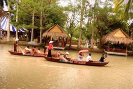 Du khách trải nghiệm chèo thuyền trên sông ở Làng du lịch Mỹ Khánh. (Ảnh: Thu Hiền/TTXVN)