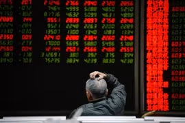 Nhà đầu tư theo dõi bảng chỉ số chứng khoán tại Bắc Kinh, Trung Quốc. (Ảnh: AFP/TTXVN) 