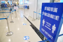 Biển báo nhắc nhở khách giữ khoảng cách tại các lối vào xếp hàng tại sân bay Nội Bài. (Nguồn: TTXVN) 