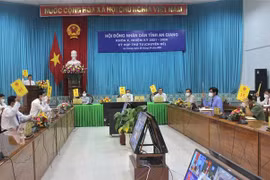 Các đại biểu tham dự kỳ họp tại điểm cầu Văn phòng Ủy ban Nhân dân tỉnh biểu quyết thông qua các nghị quyết. (Ảnh: Thanh Sang/TTXVN) 