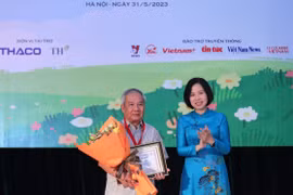 Tổng Giám đốc TTXVN Vũ Việt Trang trao Giải thưởng lớn “Hiệp sỹ Dế mèn” và chứng nhận cho nhà văn Trần Đức Tiến với truyện dài “A lô! Cậu đấy à.” (Ảnh: Hoàng Hiếu/TTXVN)