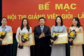 Giáo sư, Tiến sỹ Nguyễn Xuân Thắng, Ủy viên Bộ Chính trị, Chủ tịch Hội đồng Lý luận Trung ương, Giám đốc Học viện, Trưởng ban Chỉ đạo Hội thi trao bằng khen cho 4 giảng viên đạt danh hiệu Giảng viên xuất sắc. (Ảnh: Việt Đức/TTXVN) 