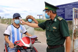Lực lượng Bộ đội biên phòng đo thân nhiệt cho lao động vào cảng. (Ảnh: Phạm Cường/TTXVN) 