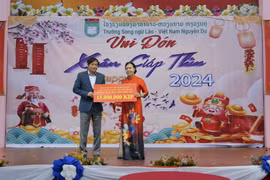 Đại sứ Việt Nam tại Lào Nguyễn Bá Hùng trao quà cho đại diện nhà trường. (Ảnh: Bá Thành/TTXVN)